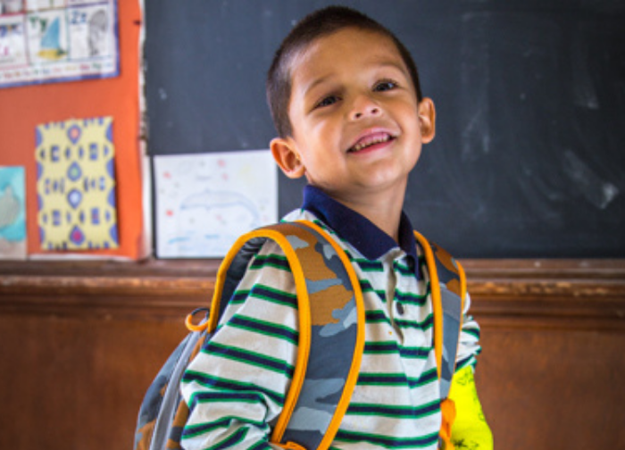 Smiling Latino boy with a backpack on